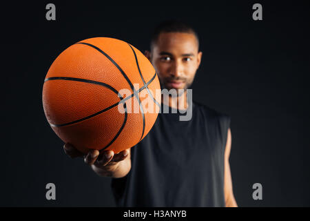 Konzentrierte sich junge schwere afrikanische Sportler geben Basketball auf schwarzem Hintergrund isoliert Stockfoto