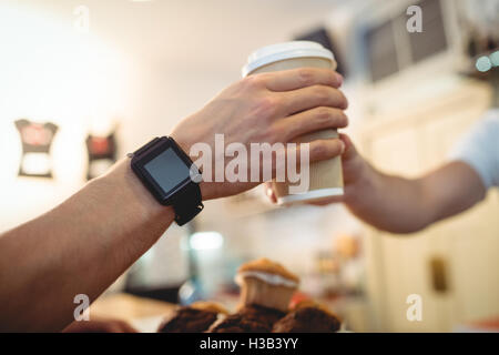 Nahaufnahme des Kunden mit smart Uhr Einnahme von Barista Kaffee im café Stockfoto