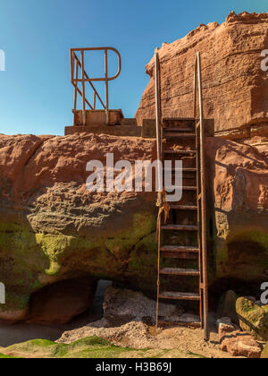 Rustikale Felsformationen sichtbar bei Ebbe und rostenden Metall Gänge an Orcome Stelle in der Nähe der Küste Stadt Exmouth, Devon. Stockfoto