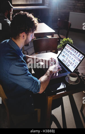 Seitenansicht des Menschen tippen auf Laptop im Café Stockfoto