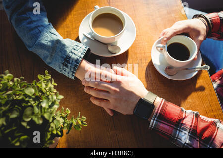 Erhöhte Ansicht von Frau und Mann Hand in Hand im café Stockfoto
