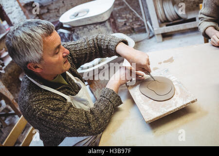 Konzentrierte Reife Töpfer arbeiten am Tisch Stockfoto