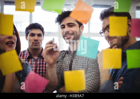 Lächelnd Geschäftsmann mit Kollegen betrachten Festhalten von Notizen Stockfoto