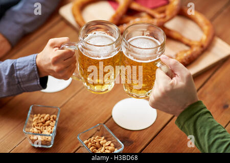 Nahaufnahme von Händen Klirren Bierkrüge in Bar oder Kneipe Stockfoto