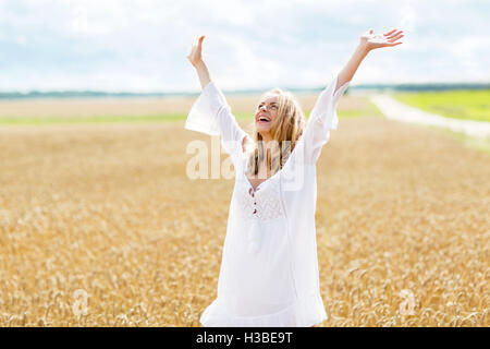 lächelnde junge Frau im weißen Kleid auf Getreide-Feld Stockfoto