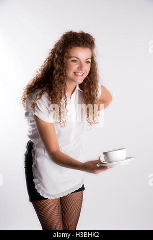 Junge attraktive Kellnerin in Uniform - einen langen lockigen Haaren Waitron eine Tasse Tee servieren Stockfoto