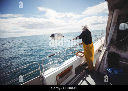 Fischer eine Boje ins Meer werfen Stockfoto