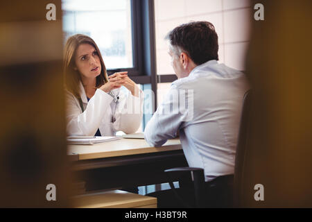 Ärztin, sitzt an ihrem Schreibtisch, im Gespräch mit Patienten Stockfoto