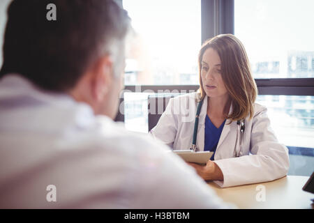 Ärztin, sitzt an ihrem Schreibtisch in Zwischenablage vor Patienten schreiben Stockfoto