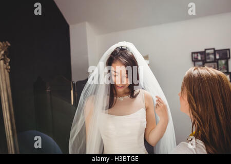 Frau versucht auf Hochzeitskleid mit Hilfe der kreativen designer Stockfoto