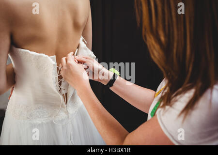 Frau versucht auf Hochzeitskleid mit Hilfe der kreativen designer Stockfoto