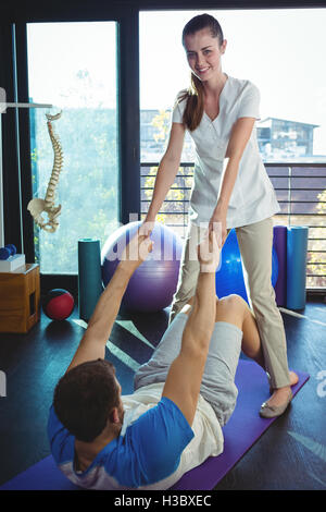 Weibliche Physiotherapeut unterstützt einen männlichen Patient während des Trainings Stockfoto