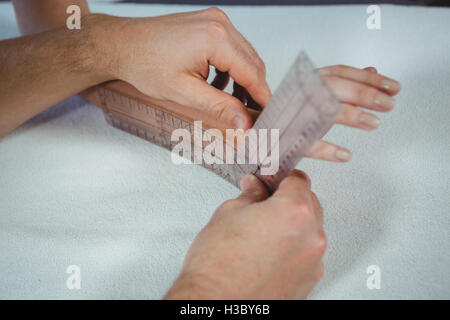 Physiotherapeuten, die Untersuchung der Patientin Handgelenk mit Winkelmesser Stockfoto