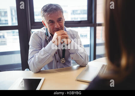 Arzt sitzt an seinem Schreibtisch im Gespräch mit Patienten Stockfoto