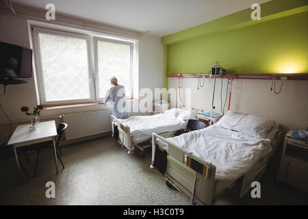 Ältere Frau stehen in der Nähe von Fenster Stockfoto