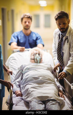 Arzt und Ward junge treibt ein senior Patient auf Keilrahmen Stockfoto