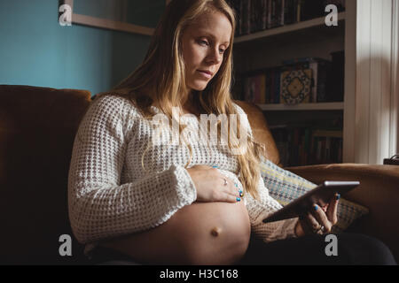 Schwangere Frau mit digital-Tablette im Wohnzimmer Stockfoto