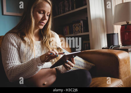 Schwangere Frau mit digital-Tablette im Wohnzimmer Stockfoto