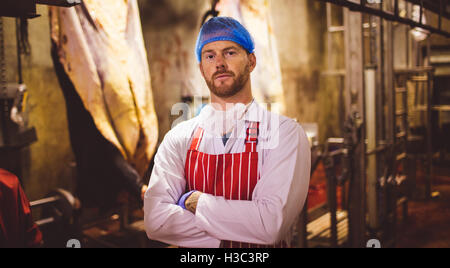 Porträt der Metzger Stand mit verschränkten in Fleisch-Lagerraum Stockfoto