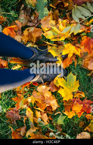 Weiblichen Beinen in Lederstiefel und Strumpfhosen auf Anhöhe mit Herbstlaub, Draufsicht, ungewöhnlichen Perspektive Stockfoto