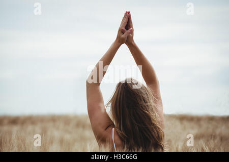 Frau mit Händen hob über Kopf im Gebet Position im Feld Stockfoto