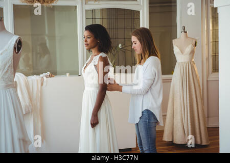 Frau versucht auf Hochzeitskleid mit Hilfe der Mode-designer Stockfoto