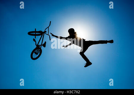 Ein extreme Fahrer macht einen freien Stil von einer Rampe springen. Der junge mit seinem Fahrrad gilt als Silhouette vor der Stockfoto