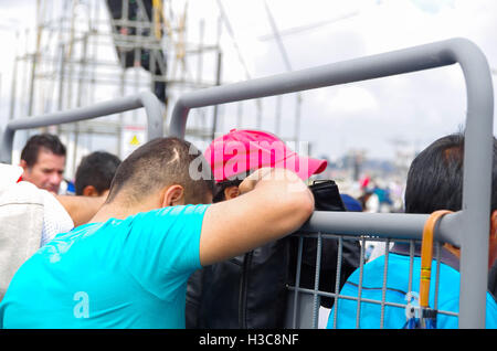 QUITO, ECUADOR - 7. Juli 2015: Ein kleiner Junge mit blauen T-shirt mit Kopf nach unten zu beten, lehnte sich gegen einen Metallzaun Stockfoto