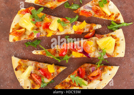 Tomate und Ananas mit Meer-Salz und Rucola-Lea über Schuss eine dünne Kruste Stein gebackene Pizza mit Pepper es geschnitten bestreut Stockfoto