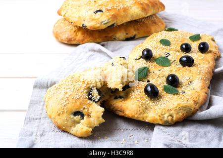 Focaccia mit Oliven, Knoblauch und Kräutern. Traditionelle italienische Hausbrot Focaccia auf Leinen Serviette. Stockfoto