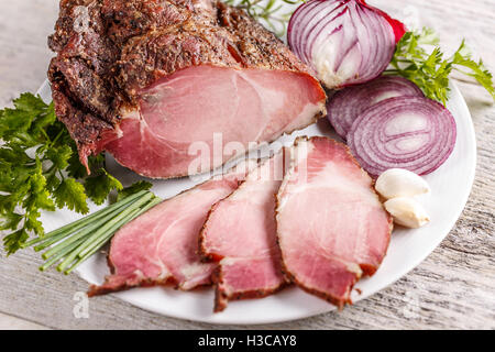 Geräucherte Schweinelende mit Gewürzen auf weißen Teller Stockfoto