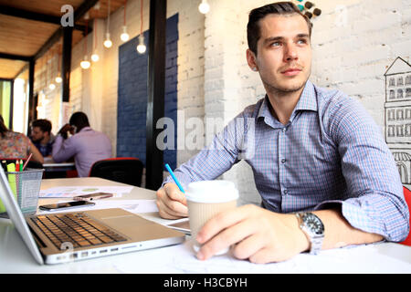Foto junge und Talente Finanzmanager mit neuen Projekt arbeiten. Hübscher Mann aus seinem Büro zu Hause arbeiten. Business-Pläne auf Laptop zu analysieren. Stockfoto