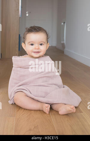 Babysitter auf Boden, in eine Decke gehüllt, Porträt Stockfoto