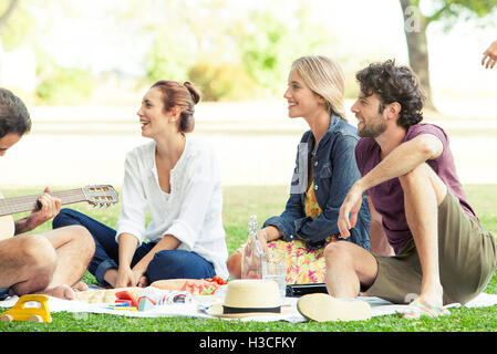 Firends anhören Mann spielt Gitarre beim Picknick im park Stockfoto