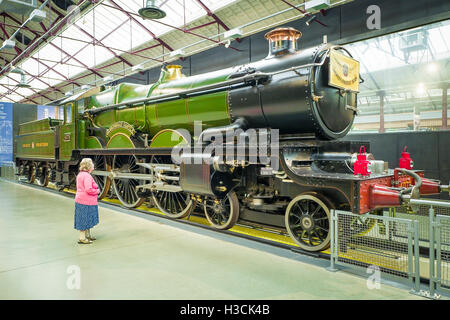 Eine Dame in den Schatten gestellt durch eine erhaltene Dampflokomotive in den 1920er Jahren erbaut und im GWR-Dampf-Museum in Swindon UK ausgestellt Stockfoto