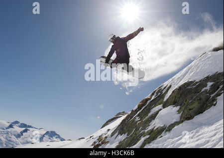 Snowboarder springt über eine Klippe im Skigebiet von Disentis 3000 Stockfoto