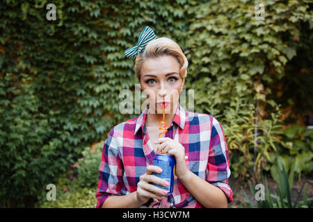 Süße verspielte Pin-up-Mädchen trinken Soda im Garten im Sommer Stockfoto