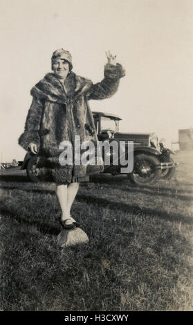 Antike c1930 Foto, balanciert Frau im Pelzmantel auf Felsen in der Nähe ein Ford-Automobile. Ort: Massachusetts, Neuengland, USA. QUELLE: ORIGINAL FOTOABZUG. Stockfoto