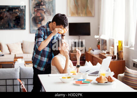 Mann hält Äpfel in aus Augen stehen durch fröhliche Frau zu Hause Stockfoto