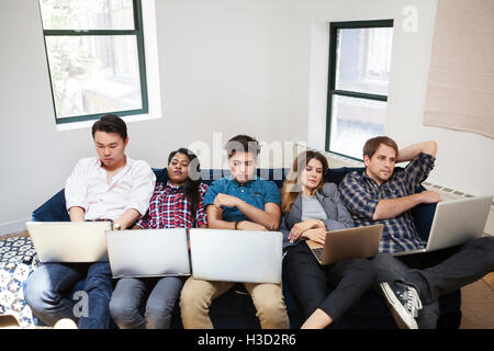 Müde Geschäftsleute mit Laptop liegen auf Sofa im Büro Stockfoto