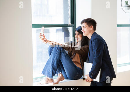 Glücklich Geschäftskollegen unter Selfie durch Smartphone durch Fenster in Kreativbüro Stockfoto