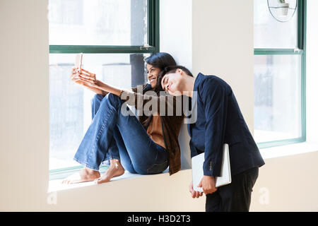 Glücklich Geschäftsfrau Selfie mit Kollegen schlafen auf der Schulter in Kreativbüro unter Stockfoto