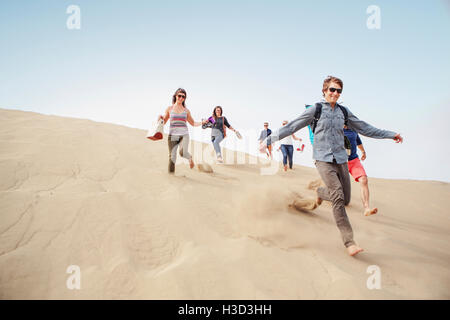 Fröhliche Freunde liefen Sanddüne gegen klarer Himmel Stockfoto