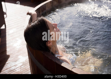 Frau in der Holzbadewanne an sonnigen Tag entspannen Stockfoto