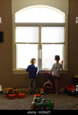 Rückansicht des jungen Blick durch Fenster zu Hause Stockfoto