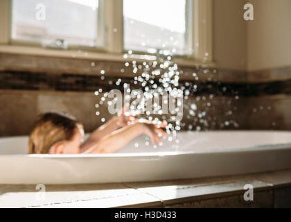 Junge Spritzwasser beim Sitzen in der Badewanne Stockfoto