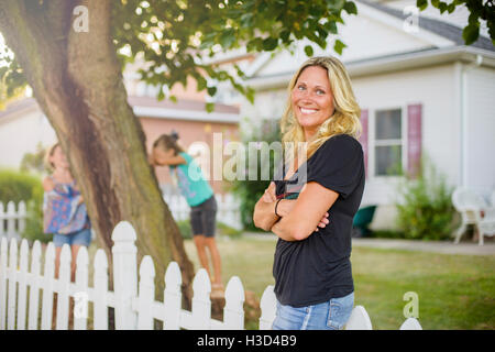 Glückliche Frau wegsehen, während die Kinder spielen verstecken und suchen im Hinterhof Stockfoto