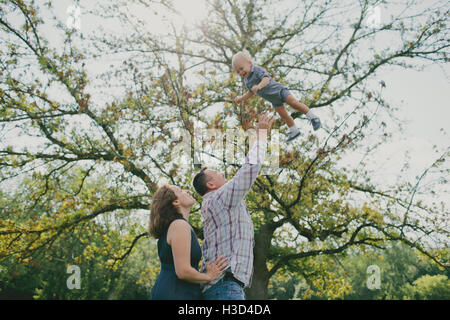 Fröhlicher Mensch mit Frau Sohn in die Luft werfen Stockfoto