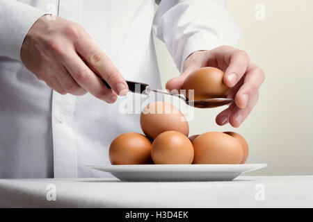 Mittelteil der Küchenchef hält braune Ei in Löffel Stockfoto