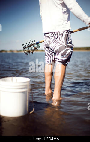 Geringen Teil der Mann hält Muschel Rechen am Strand Stockfoto